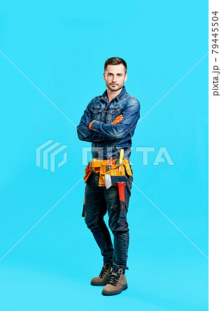 Full length portrait of confident handsome male construction worker staying over blue background Full length portrait of confident handsome male construction worker staying over blue background 79445504