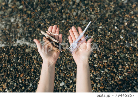 The concept of a person's choice: to preserve nature or use disposable plastic. In one hand, the woman holds wooden branches, in the other - plastic waste. The concept of a person's choice: to preserve nature or use disposable plastic. In one hand, the woman holds wooden branches, in the other - plastic waste. 79445857