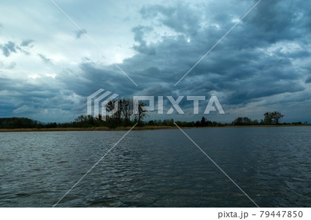 Restless evening clouds over a calm lake 79447850