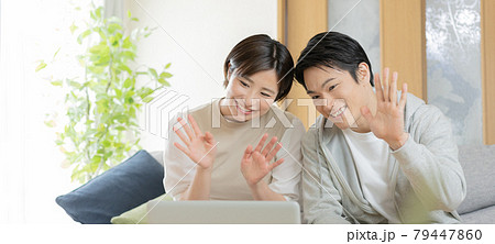 テレビ電話で実家の両親と会話をする若い夫婦　バナーサイズ 79447860