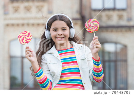 Her favorite sweet. girl in headphones. little girl in wireless headset with lollipop. Her favorite sweet. girl in headphones. little girl in wireless headset with lollipop. 79448705