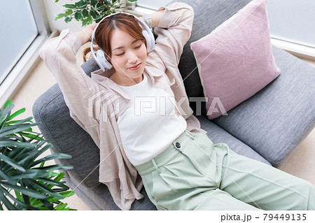 ヘッドフォンで音楽を聴きながらリラックスする若い女性 ヘッドフォンで音楽を聴きながらリラックスする若い女性 79449135