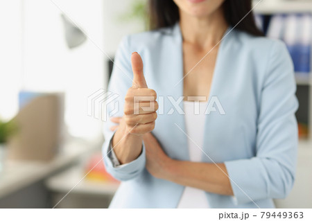 Businesswoman in suit holds thumbs up in office 79449363