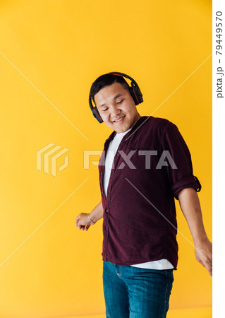 Beautiful Asian man dances to music in headphones Beautiful Asian man dances to music in headphones 79449570