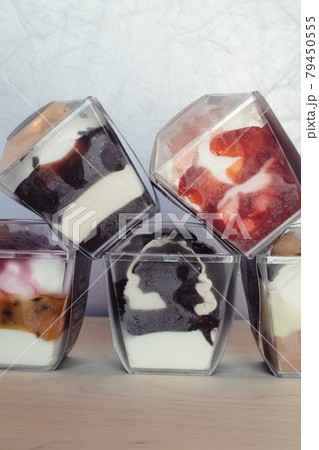 Close-up of multi-colored layered ice cream. Creative food. Vegetarian sweets. Dessert in a glass in a restaurant or cafe. Soy milk, chocolate and fruits in a beautiful dish 79450555