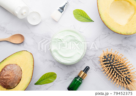 Beauty natural skincare and hair care products made with avocado. Top view of hair mask in bowl with serum, shampoo, comb, brush and fresh organic avocado on marble backgound. 79452375