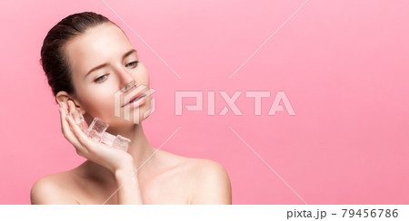 Beautiful woman with natural looking makeup holding ice cubes near face 79456786