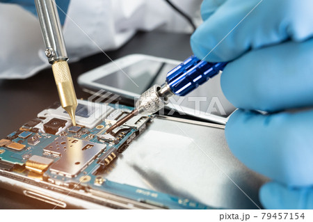 Technician repairing inside of mobile phone by soldering iron. Integrated Circuit. the concept of data, hardware, technology. 79457154