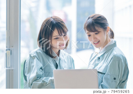 オフィスでパソコンを見ながら相談する作業着の若い女性エンジニア 79459265