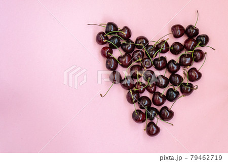 Heart shaped red cherries on a pink background. Cherry background. Sweet cherry isolated on pink background cutout. Copy space Heart shaped red cherries on a pink background. Cherry background. Sweet cherry isolated on pink background cutout. Copy space 79462719