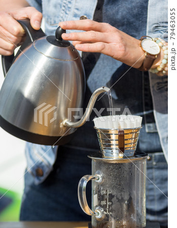 Drip brewing, barista makes fresh filtered coffee at the outdoor coffee shop. First spring day with bright warm sun after a long winter. 79463055