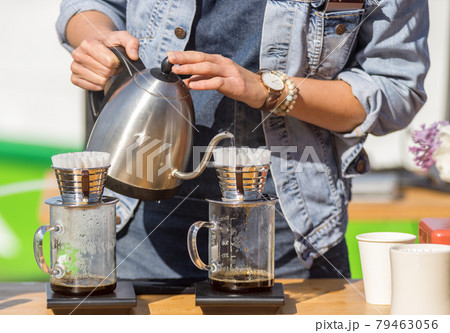Drip brewing, barista makes fresh filtered coffee at the outdoor coffee shop. First spring day with bright warm sun after a long winter. 79463056