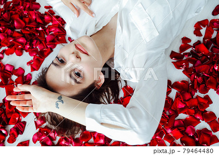 beautiful woman lies among the red petals of rose flowers 79464480