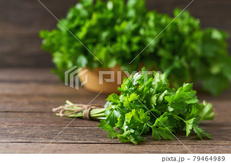 fresh parsley in a wooden bowl on the table, selective focus, rustic style. 79464989