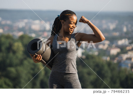 Smiling african woman showing her biceps outdoors 79466235