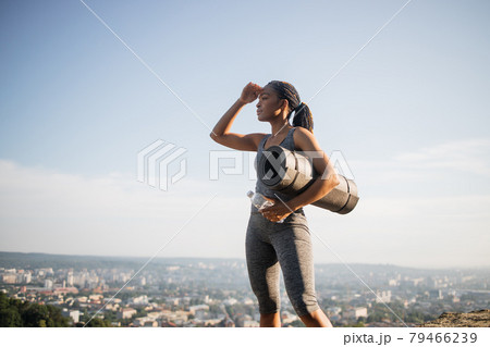Fitness black woman holding yoga mat and water bottle Fitness black woman holding yoga mat and water bottle 79466239