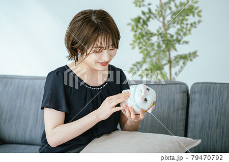 貯金箱と若い女性 79470792