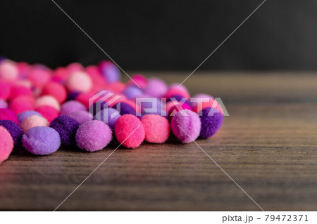 Colorful pom pom on dark wood background 79472371
