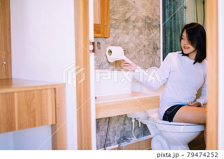 Young asian woman using toilet paper and using toilet in morning at home 79474252