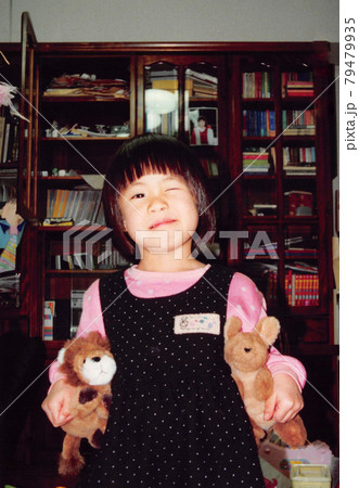 ぬいぐるみを持っているウインクする小さな女の子 ぬいぐるみを持っているウインクする小さな女の子 79479935