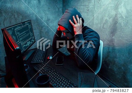 Anonymous internet hacker with mask sitting at the table and using computer Anonymous internet hacker with mask sitting at the table and using computer 79483827
