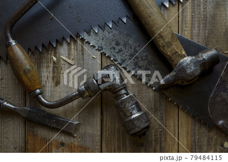 Vintage tools are hacksaw, chisel, hammer and drill on workbench in workshop 79484115