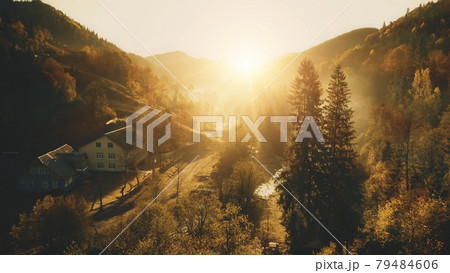 Sun over mountain village aerial. Autumn nature landscape. Sunny pine trees forest at cottages 79484606