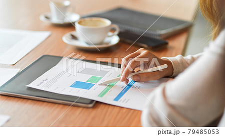 Businesswoman reading financial report while holding stylus pen on the wooden desk Businesswoman reading financial report while holding stylus pen on the wooden desk 79485053