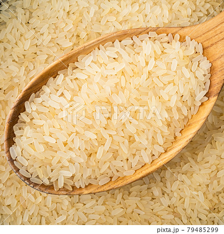 raw parboiled rice in wooden spoon closeup 79485299
