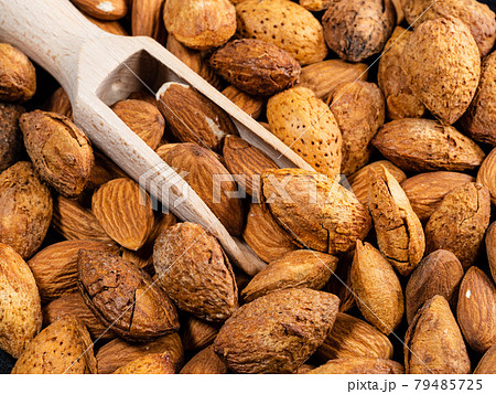 wooden scoop in almond drupes and seeds closeup wooden scoop in almond drupes and seeds closeup 79485725