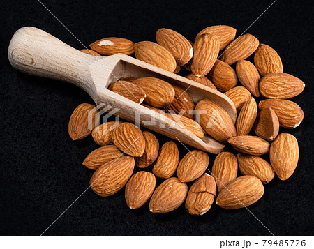 wooden scoop in almond seeds on black plate wooden scoop in almond seeds on black plate 79485726