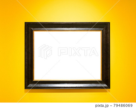 wide black wooden picture frame on yellow wall 79486069