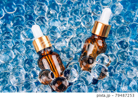 Mockup image of two dropper bottles with natural organic herbal cosmetic oil on blue background of water gel balls. Trendy still life composition with copy space. Modern organic apothecary concept Mockup image of two dropper bottles with natural organic herbal cosmetic oil on blue background of water gel balls. Trendy still life composition with copy space. Modern organic apothecary concept 79487253