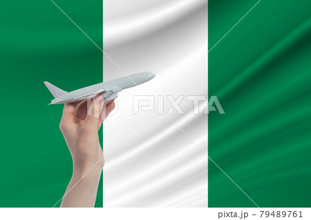 Airplane in hand with national flag of Nigeria. Travel to Nigeria Airplane in hand with national flag of Nigeria. Travel to Nigeria 79489761