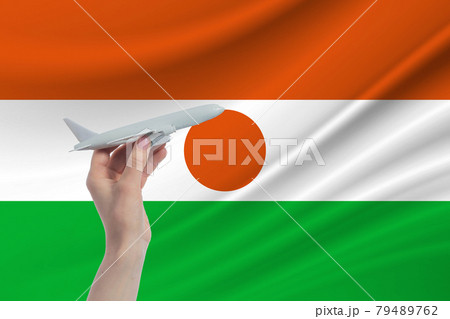 Airplane in hand with national flag of Niger. Travel to Niger Airplane in hand with national flag of Niger. Travel to Niger 79489762
