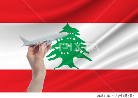 Airplane in hand with national flag of Lebanon. Travel to Lebanon 79489787