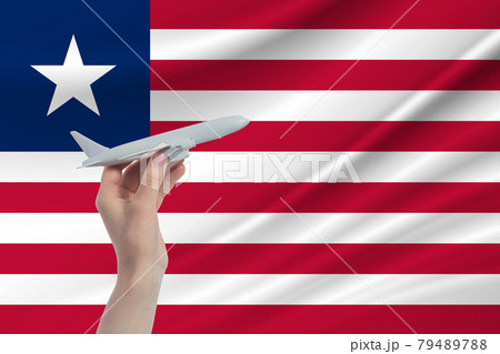 Airplane in hand with national flag of Liberia. Travel to Liberia 79489788