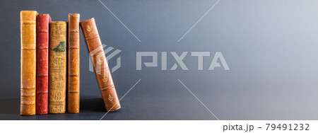 Row of old books on dark background banner 79491232