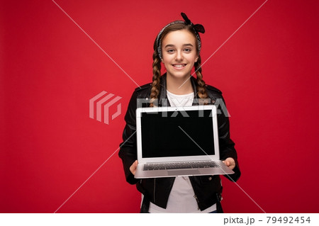 Photo of beautiful young girl holding computer laptop looking at camera isolated over colourful 79492454
