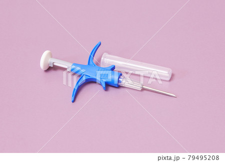 a syringe with a microchip for identifying animals on a pink background, close-up a syringe with a microchip for identifying animals on a pink background, close-up 79495208