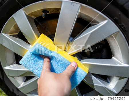 Hand washing car rims with a sponge with car shampoo for cleaning dirt and giving shine 79495292