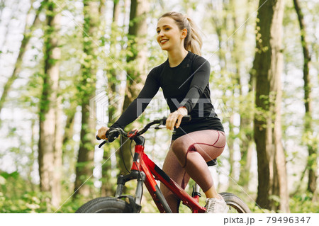 Woman riding a mountain bike in the forest Woman riding a mountain bike in the forest 79496347