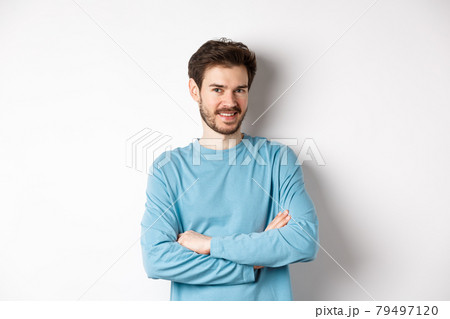 Confident young man with beard, cross arms on chest and smile at camera, standing like professional over white background 79497120