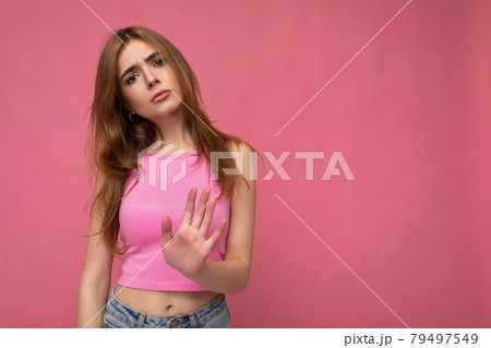 Serious upset young attractive dark blonde woman with sincere emotions isolated on background wall 79497549