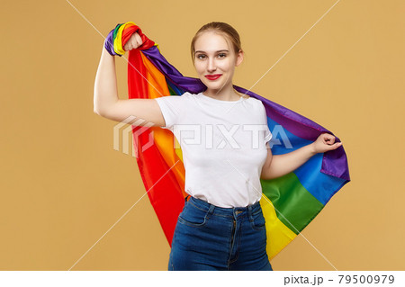 attractive blonde made posing with a rainbow LGBT flag. photo shoot in the studio on a yellow background 79500979