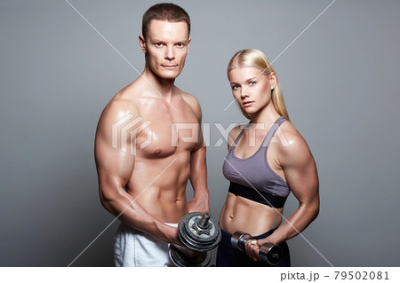 couple of bodybuilders. muscular Man and beautiful blond girl with dumbbells 79502081