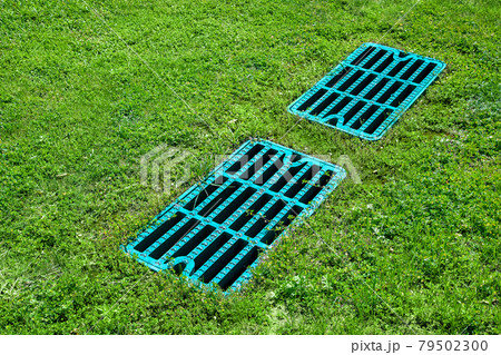 manhole drainage grates on the lawn with green grass septic tank cover, sump cesspool drainage system environment design side view with copy space, nobody. 79502300