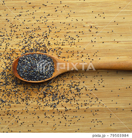 Fresh and fine grained poppy seeds in wooden spoon on bamboo cutting board Fresh and fine grained poppy seeds in wooden spoon on bamboo cutting board 79503984