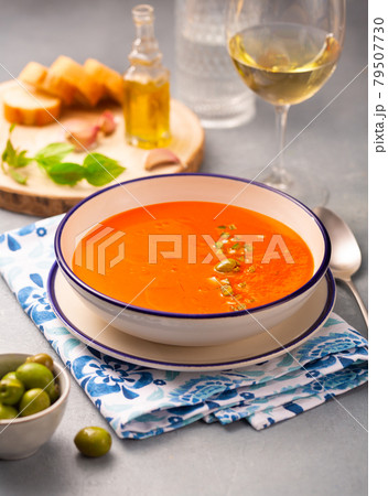 Spanish dish gazpacho in a white plate on a napkin with a pattern and a glass of wine Spanish dish gazpacho in a white plate on a napkin with a pattern and a glass of wine 79507730