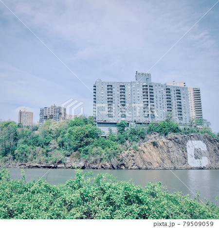 View of Hudson Park from Inwood Hill Park in New York. A cliff with a graffiti "C ", and a blue residence. 79509059
